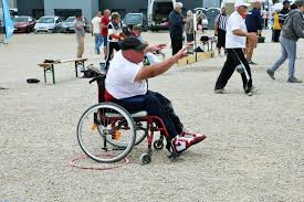 This photograph shows a player in a wheelchair with one wheel positioned in the playing circle and after playing their boule.
